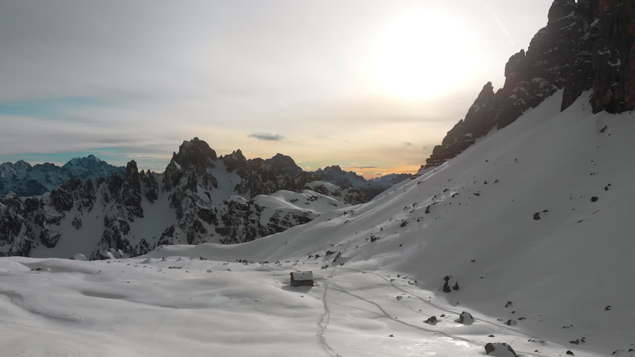Vista aerea delle Dolomiti innevate con baita isolata al tramonto
