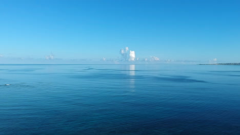 Cielo-Azul-A-Primera-Hora-De-La-Mañana-Reflejándose-En-El-Océano-Con-Algunas-Nubes-Cumulonimbus-En-El-Horizonte