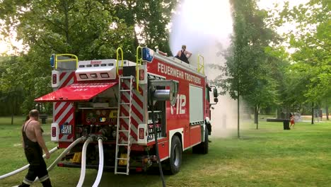 german firetruck spraying water for kids and trees on a hot summer day-6