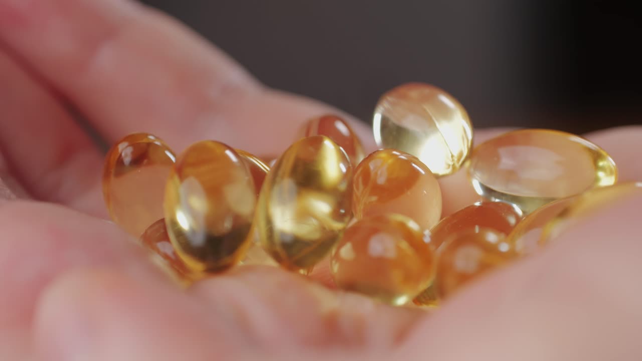 Omega fish oil gel capsules on man hand close-up macro . Human keeps in hands Omega vitamins pills 3 6 9. To be healthy and take care of your health. Pharmaceutical industry. Business of biological supplements and vitamin.