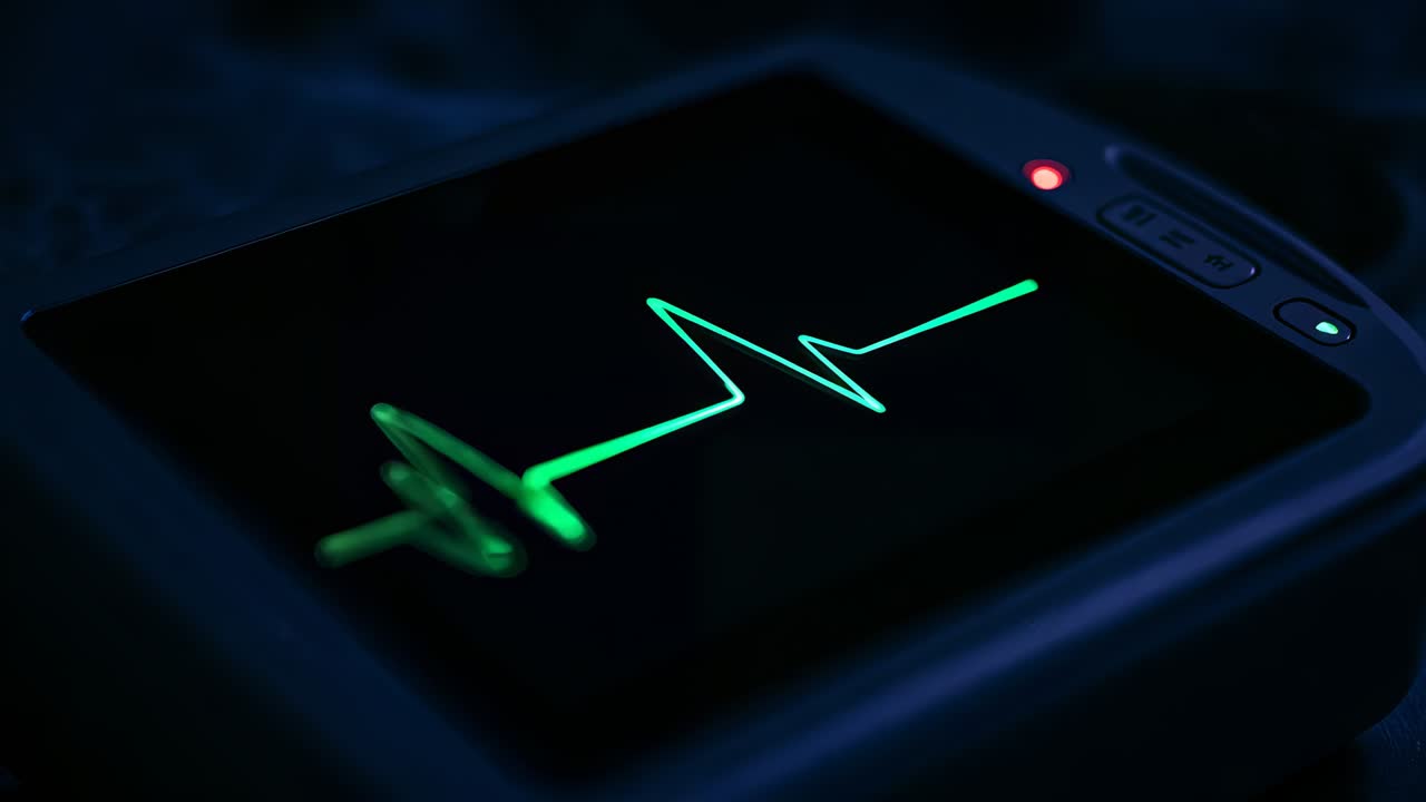 Displaying signal ECG trace, monitor showing green waveform then going flat at lab bench, red LED