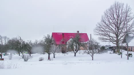 雪覆蓋的鄉村風景,顯示小屋和裸樹的雪融化