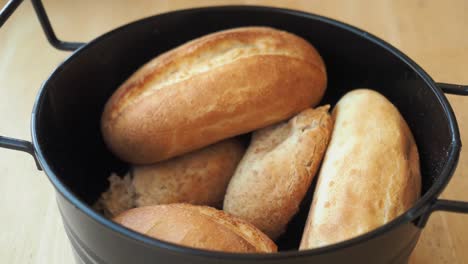 closeup of a basket of fresh bread rolls on a wooden table