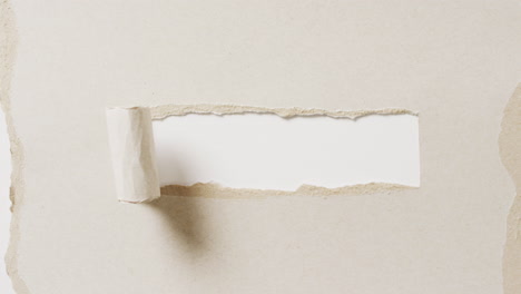 video de primer plano de un pedazo de papel beige roto sobre un fondo blanco