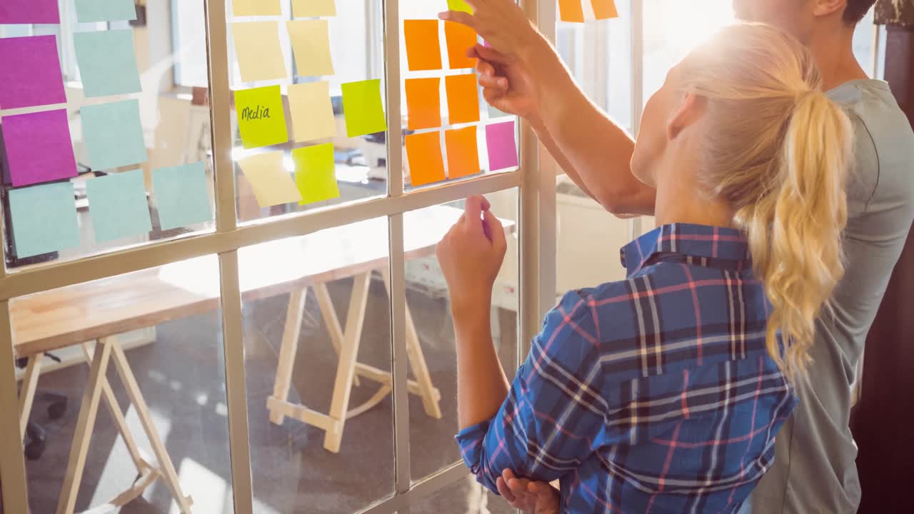 video de creativos colegas caucásicos masculinos y femeninos escribiendo notas en una oficina moderna