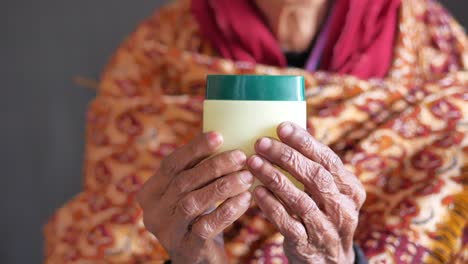 Senior-woman-using-petroleum-jelly-onto-skin-at-home-close-up