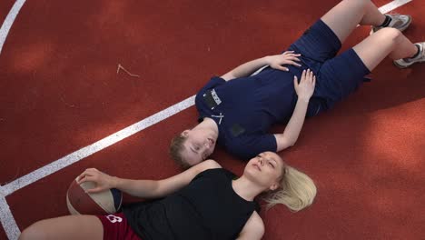 two women basketball players resting on a court