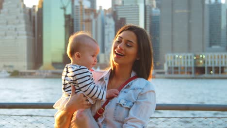 young mother with daughter standing at riverside, manhattan