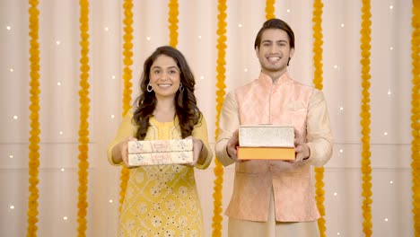pareja india deseando un feliz diwali y ofreciendo cajas de regalos a la cámara