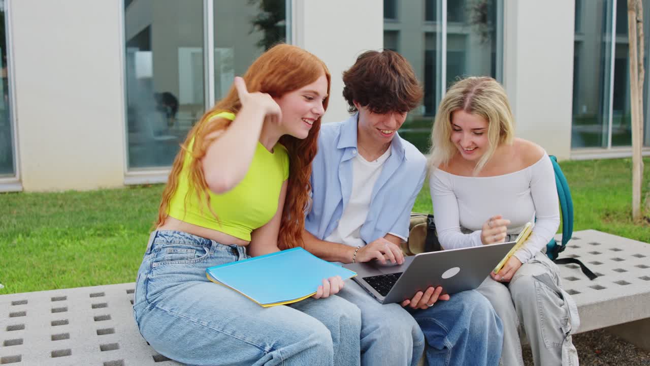 Gruppe af studerende, der studerer sammen på campus med en bærbar computer