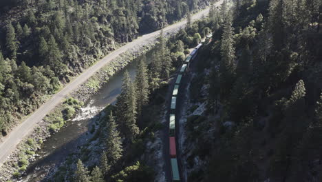 bosque nacional de plumas con un largo tren de carga que viaja a través del valle de abajo