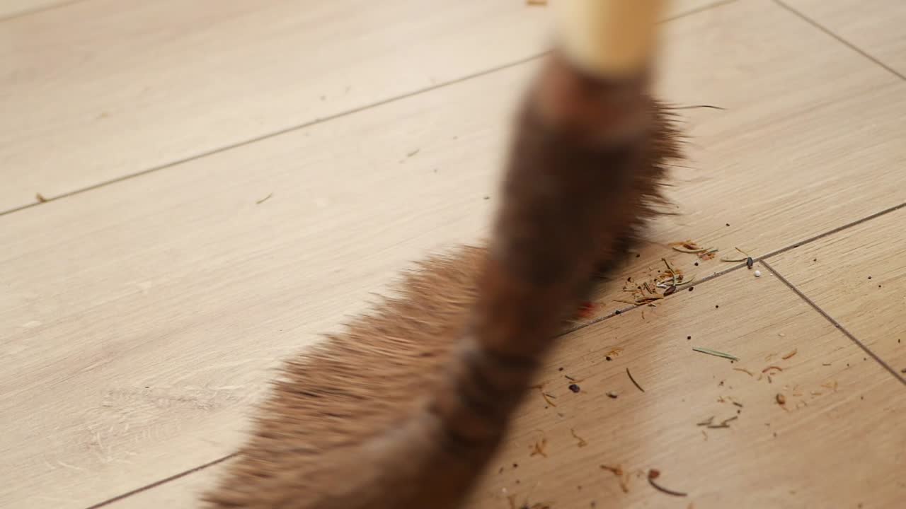 Koště zametající špínu a nečistoty z dřevěné podlahy