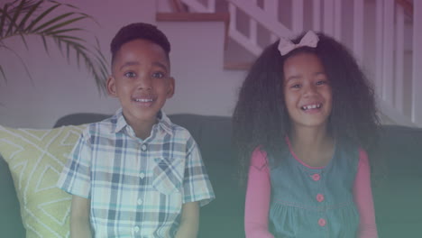 puntos de luz contra el retrato de un hermano y una hermana afroamericanos sonriendo sentados en el sofá