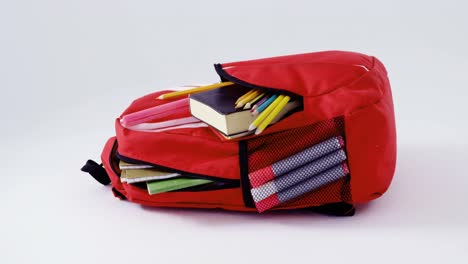 schoolbag with various supplies on white background