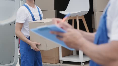 two young workers of removal company are loading boxes and furniture into a minibus