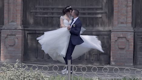 handsome-fiance-holds-and-spins-bride-in-long-white-dress