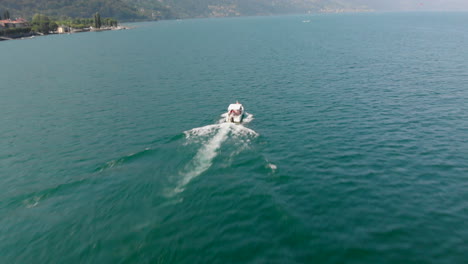 Aerial-crane-shot-of-a-motorboat-cruising-at-Lago-Maggiore,-Italy