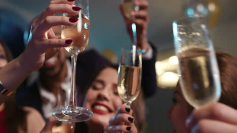 friends holding up champagne flutes together in a toast at party