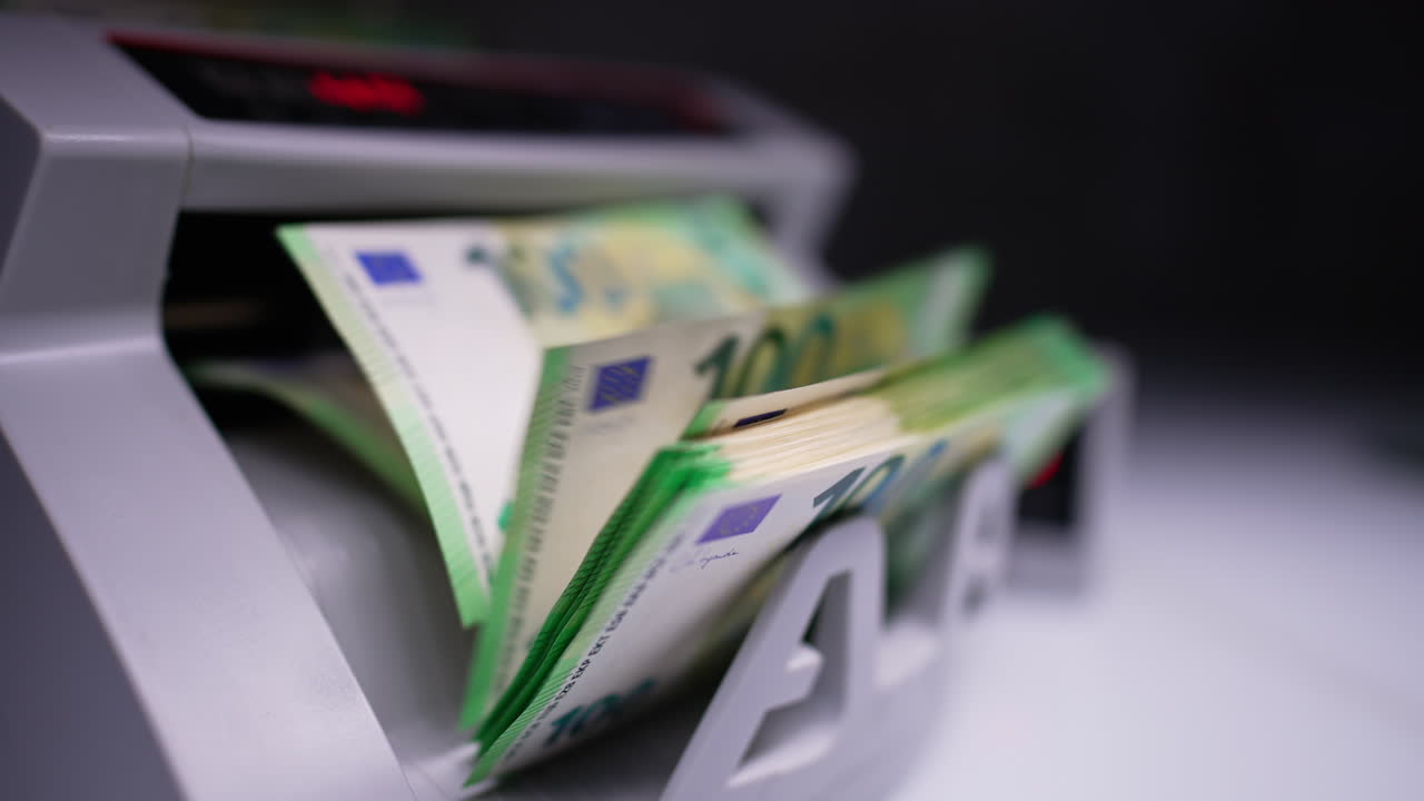 Money counting machine with one hundred euro bills. Fifty euro banknotes appear after hundreds. Close up.