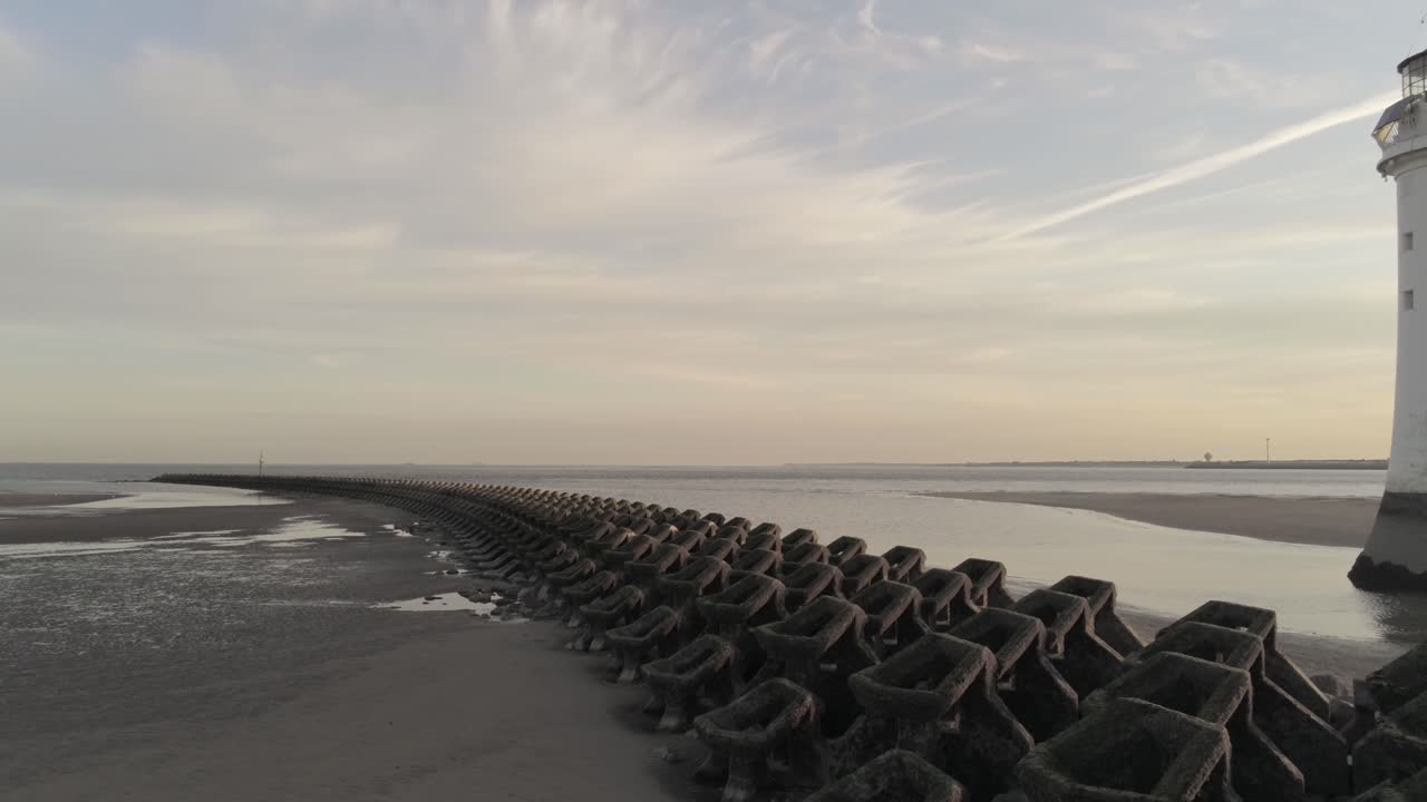 일출의 극적인 황금시간대 영국 등대를 가로지르는 공중 느린 낮은 오른쪽 팬 뷰