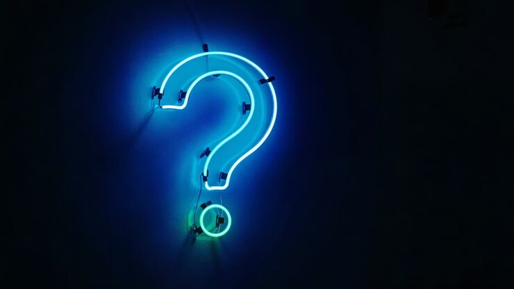 Glowing cyan neon question-mark drawing power via wiring, casting halo on dark wall with green dot
