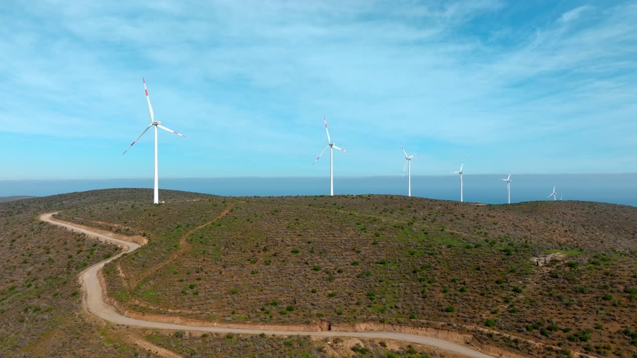 vista aérea de una cadena de turbinas eólicas en un día soleado en las áridas montañas del norte de chile