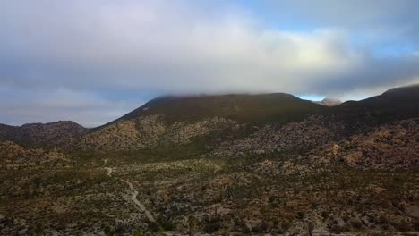 Vista-Aérea-Sobre-Un-Desierto-Hacia-Una-Montaña-Cubierta-De-Nubes,-Día-Parcialmente-Soleado,-En-Catavina,-México---Dolly,-Tiro-De-Drones