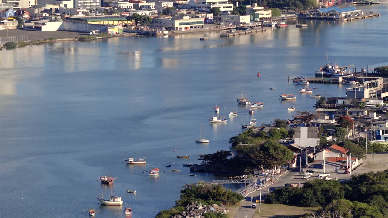 Drone moves left over Itajaí’s anchored boats, clubhouse, and city in afternoon