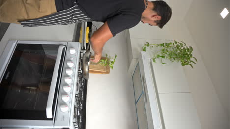 movimiento lento vertical de un hombre latino mexicano en forma disfrutando de un gran tiempo en la cocina cocinando bailando y cantando con pantalones cortos y una camiseta