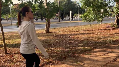 Sporty-thin-Latina-woman-with-ponytail-walks-on-sidewalk-in-urban-area