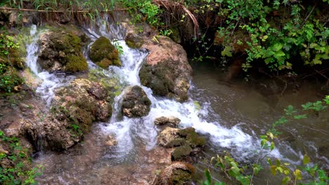 agua que fluye a través de grandes rocas cubiertas de musgo en el parque nacional de krka en croacia