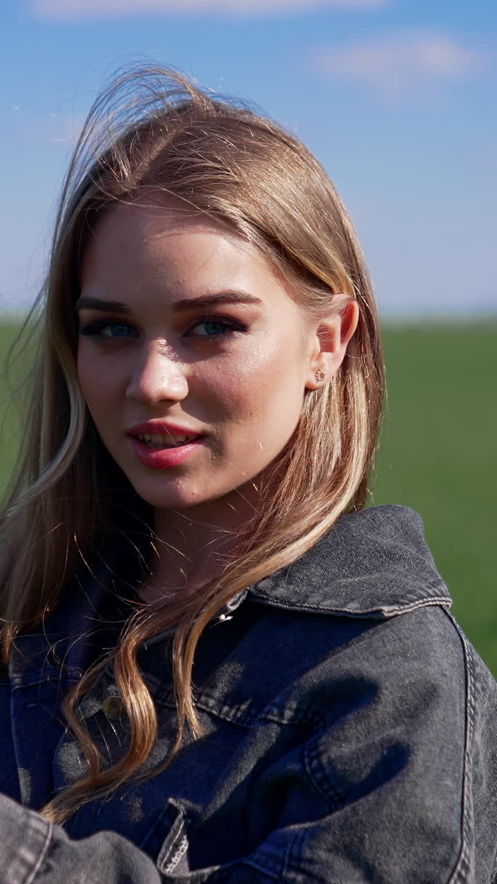 Portrait of attractive young woman outdoors. Pretty model in the countryside. Beautiful village girl posing on camera on nature background. Vertical video
