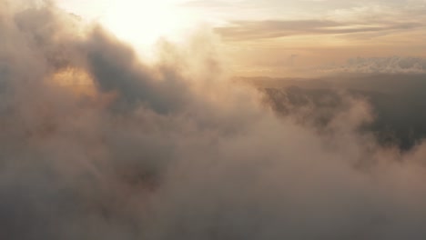 Aerial-view-flying-through-light,-heaped-up-and-wispy-clouds-in-golden-sunset,-sunrise