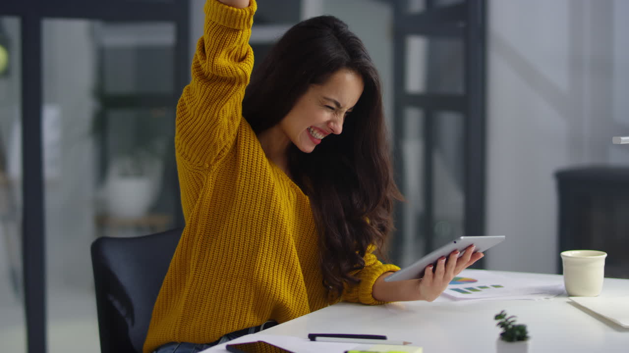 Successful businesswoman making winner gestures in modern office