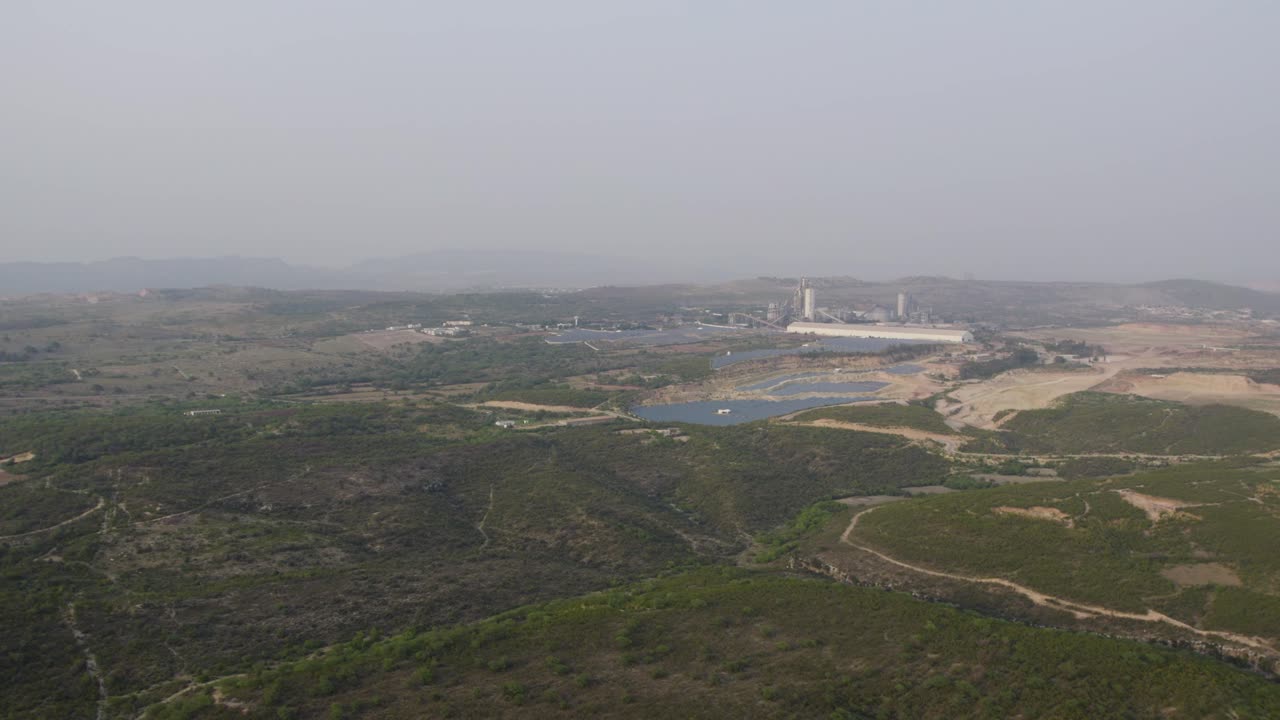 Wide aerial view of Swaik Lake, industrial site, green hills at Kallar Kahar. Punjab, Pakistan