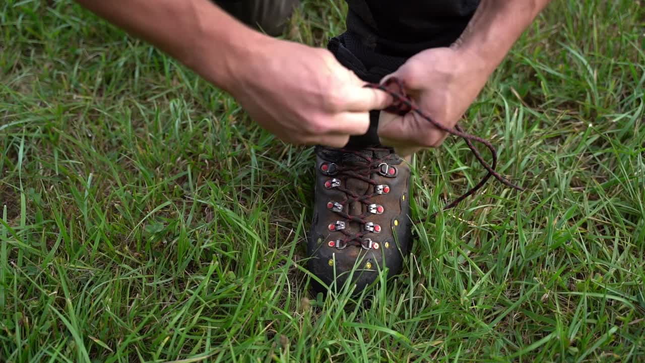 Un uomo allaccia le sue scarpe da lavoro forestale, preparandosi per compiti di silvicoltura in un ambiente naturale all'aperto.
