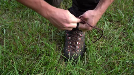a man ties his forest work shoes, preparing for forestry tasks in a natural outdoor setting