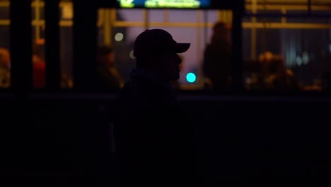 Epic-silhouette-of-male-standing-still-as-city-life,-people,-and-metro-pass-by