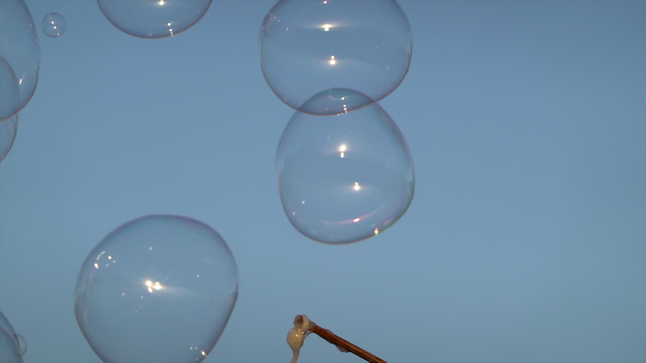 Colorful soap bubbles floating against the blue evening sky during a street performance