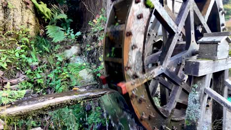 wooden water wheel rotating by the force of water in the preserved post town of magome juku, kiso valley, japan