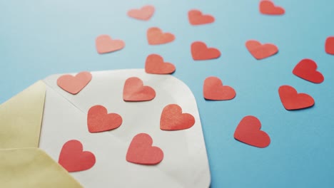 envelope with paper hearts on blue background at valentine's day