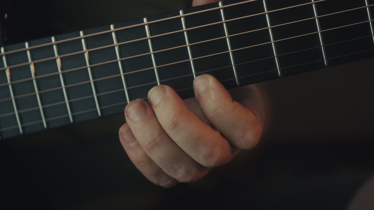 Musician's Hand Pressing Strings on Acoustic Guitar Fretboard