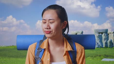 close up of asian female hiker with mountaineering backpack shaking her head and making unsatisfied face while traveling in stonehenge