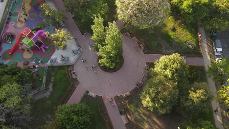 Aerial-tilt-down-shot-of-many-people-in-public-walking-on-path-in-park-during-sunset---Buenos-Aires,-Argentina