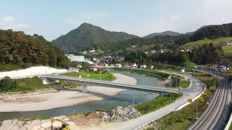 Drone-view-of-River-between-highways-in-Marija-Gradec,-Laško-with-mountains-in-the-background,-Slovenia