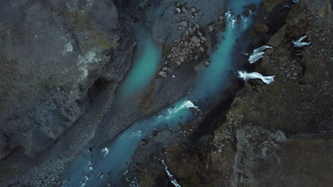 aqua blue river and waterfalls in highlands of iceland, high angle drone aerial view