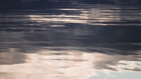 clouds lit by the warm sun are reflected in the rippled surface of water