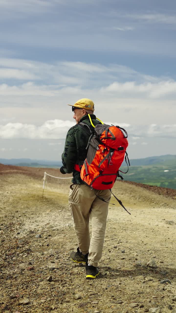 Hombre con mochila haciendo senderismo en un sendero de montaña rocoso