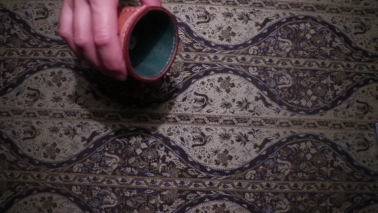 Persona che lancia i dadi in un bicchiere portadadi.