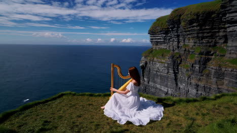 woman playing harp on a grassy cliff overlooking the ocean